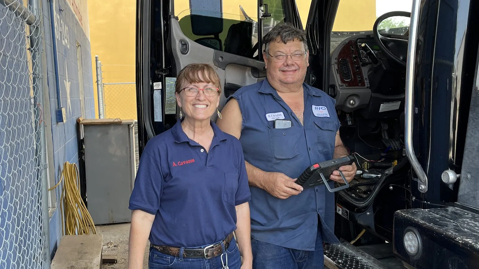 Rey and Ana Cavazos standing at the open door of a heavy duty truck outside Rio Auto Electric