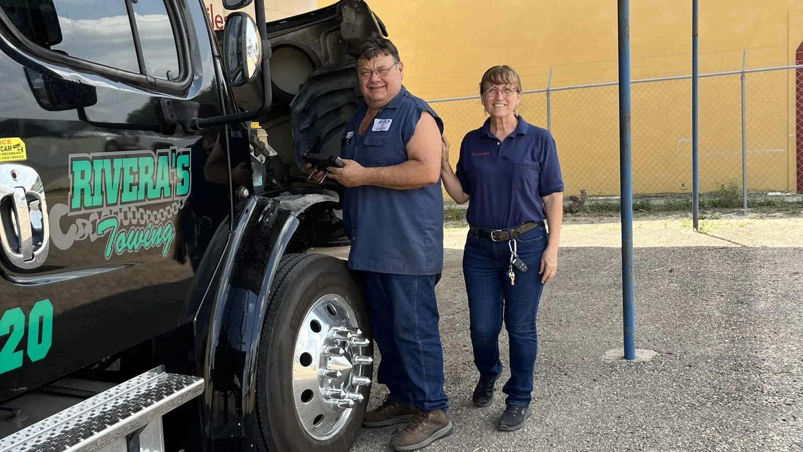 Rey and Ana Cavazos beside a commercial heavy duty truck outside the shop