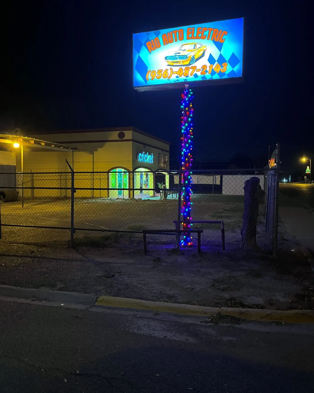 The Rio Auto Electric sign lit up at night on West Main Street