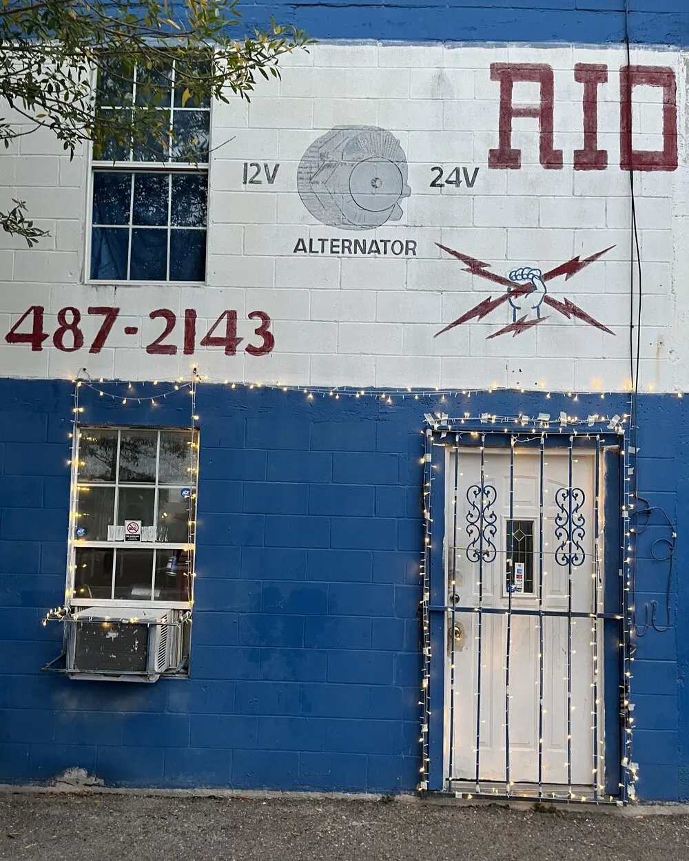 The hand painted 12V and 24V alternator sign with the shop phone number on the side of the Rio Auto Electric building